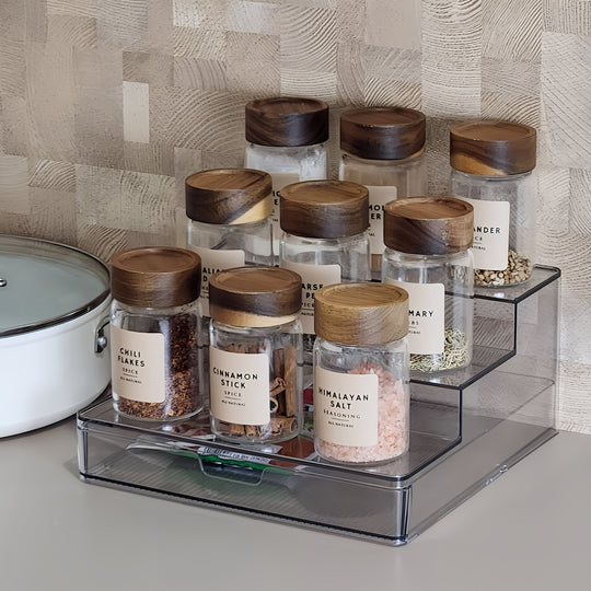Set of spice jars with wooden lids on a kitchen shelf.